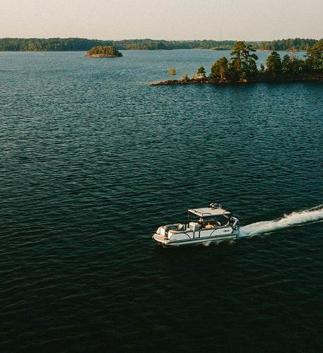 Boat cruising on a lake with small wooded islands in the distance.