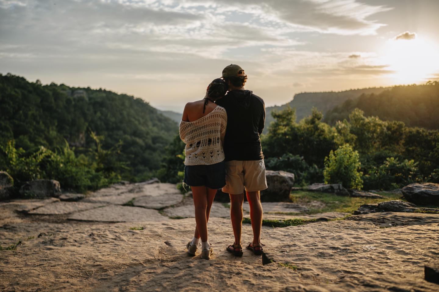 Couple embraces at scenic overlook during sunset.