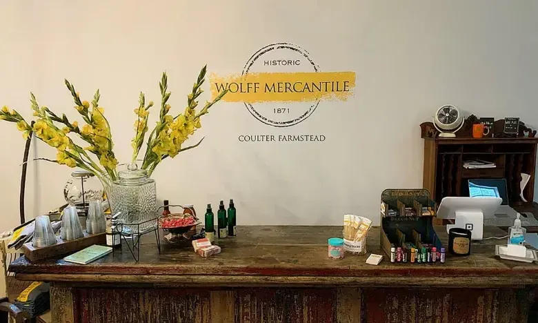 Rustic wooden counter with flowers and small products on display.