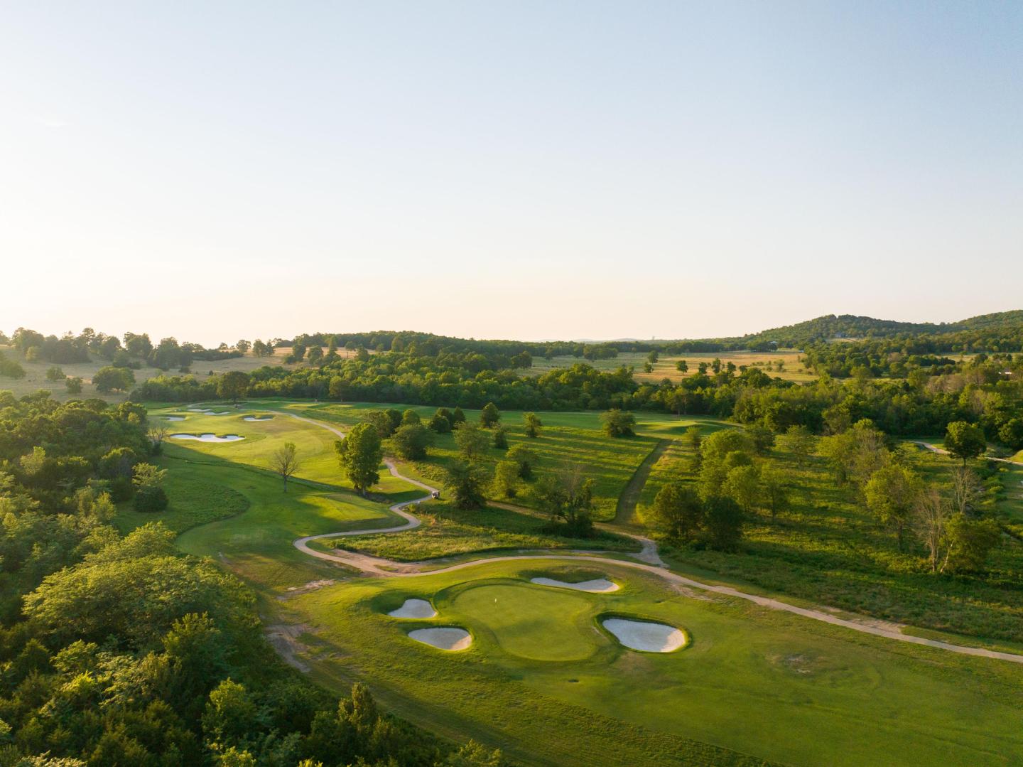Aerial view of a lush green golf course at sunrise.
