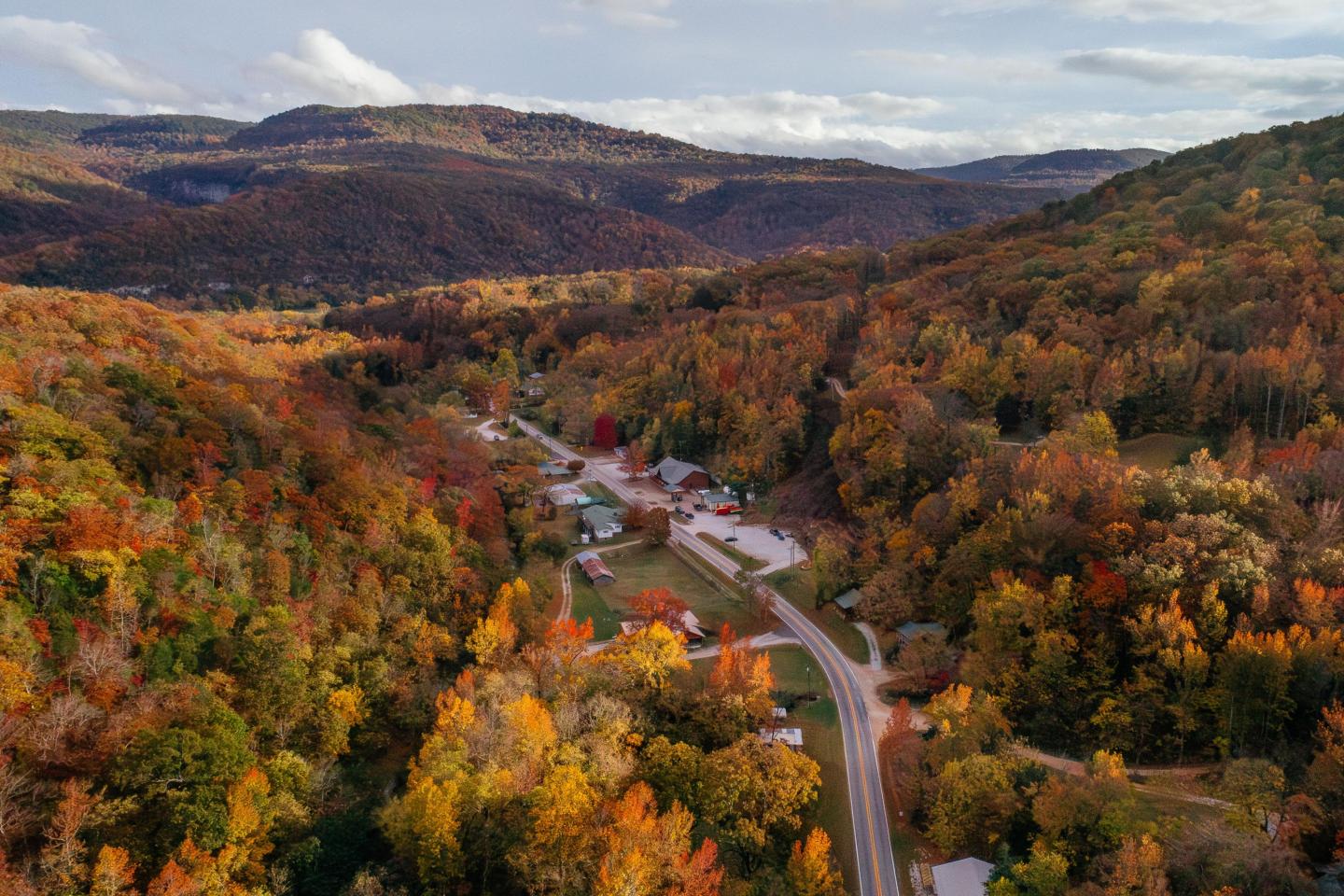 Aerial view of a winding road through colorful autumn forested hills.