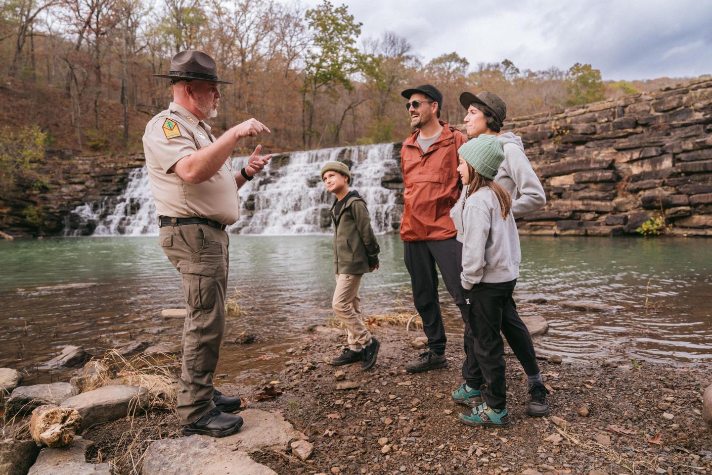 Park ranger talking to family by a waterfall.