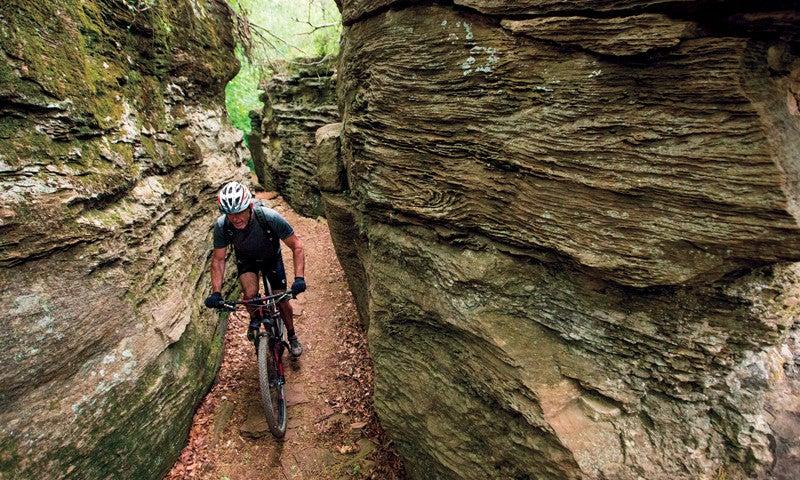 Cyclist navigating a narrow rocky trail in a canyon.