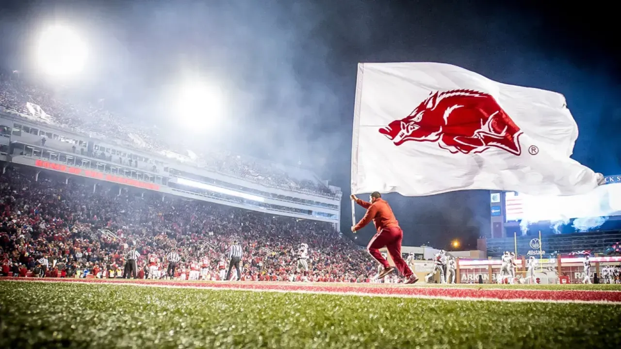 Person runs with large white flag on a football field at night.