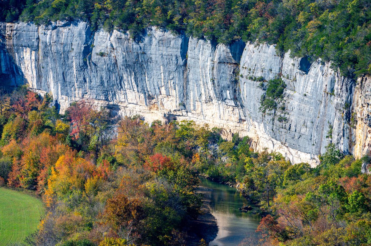 Cliff face with autumn trees and a winding river below.