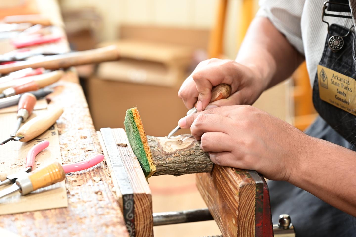 Woodcarver chiseling wood in a workshop.