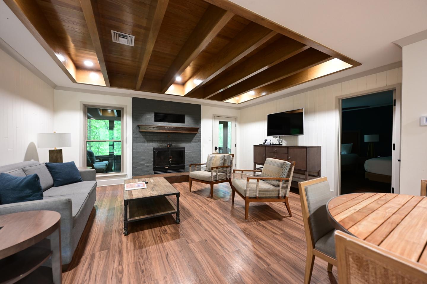 Modern living room with wooden beams, sofas, and a round dining table.