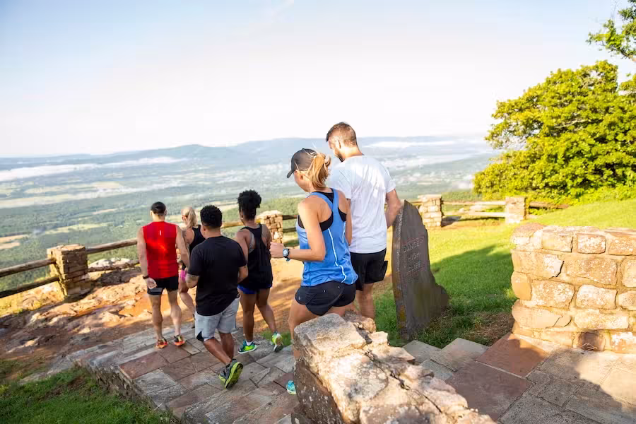 Group hiking on a sunny day, overlooking a scenic valley.