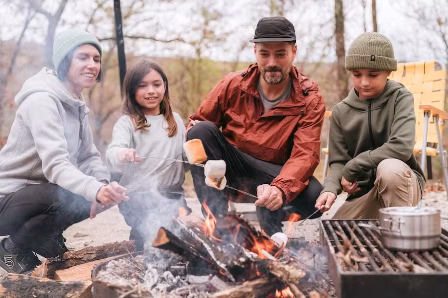 Family roasting marshmallows around a campfire outdoors.