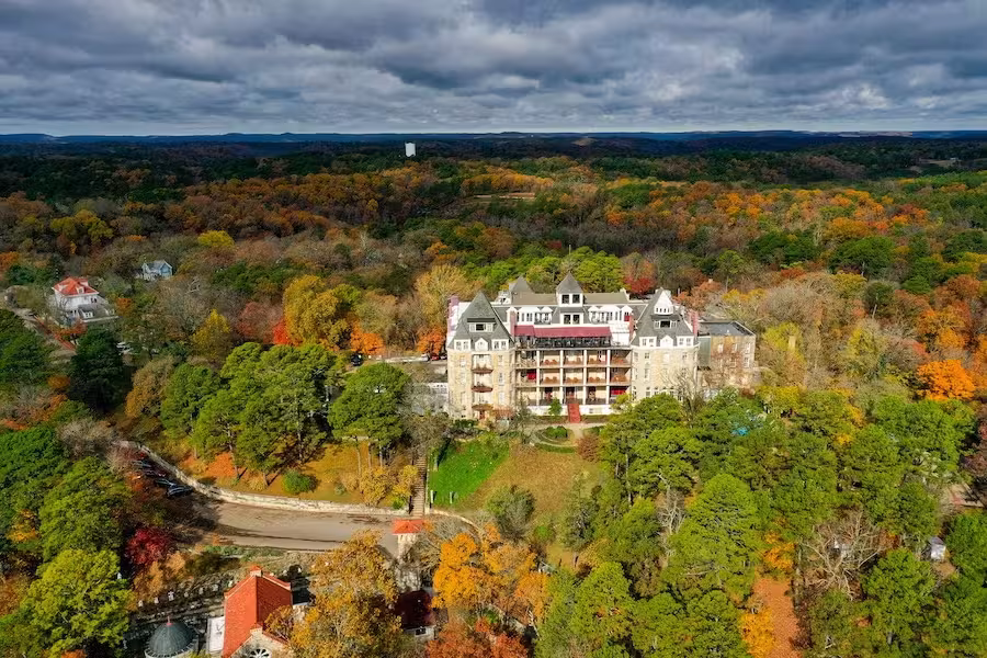 Aerial view of a large historic building surrounded by autumn trees.