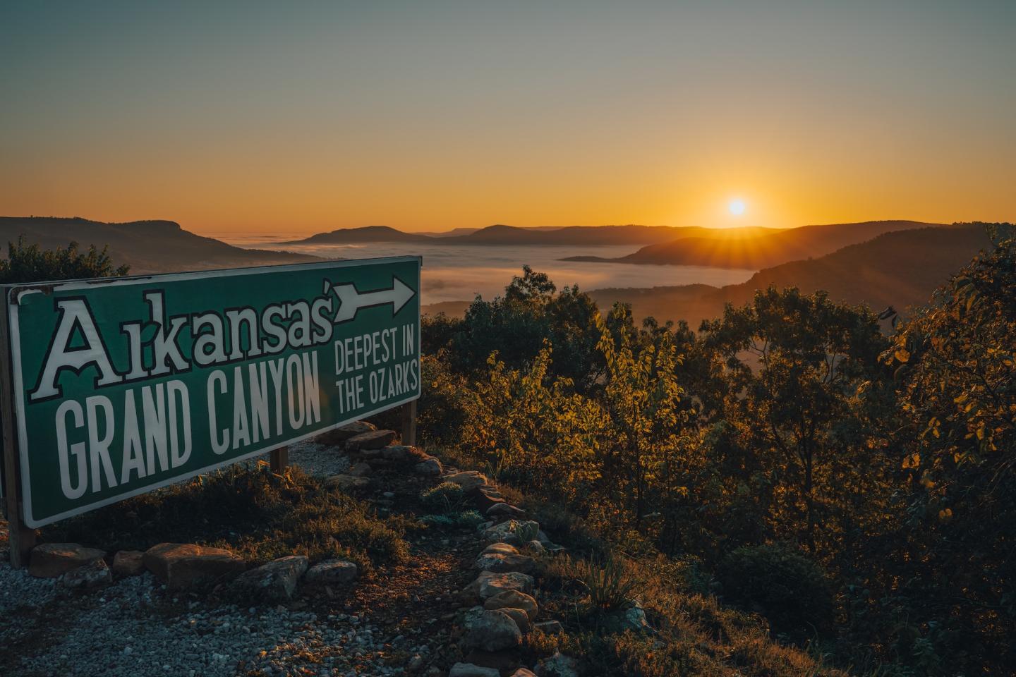 Sunrise over Arkansas hills with a sign in the foreground.