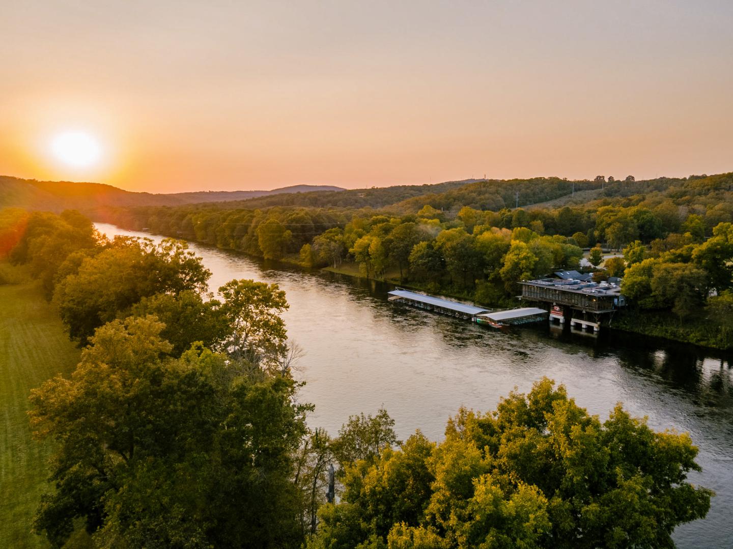 Sunset over a river surrounded by lush green trees.