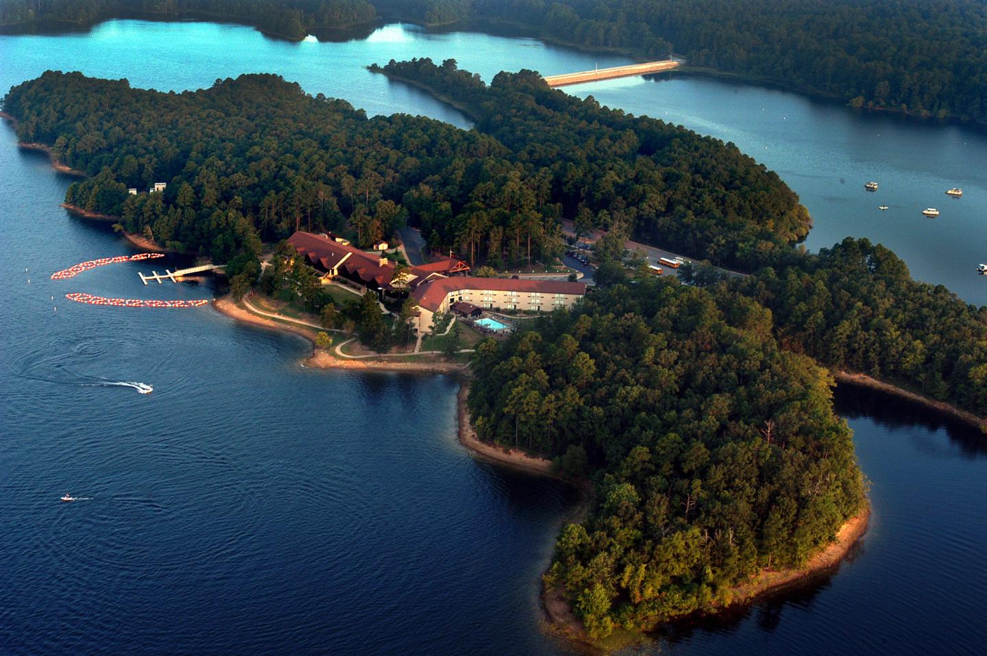 Lush island with resort, surrounded by blue lake waters and boats.