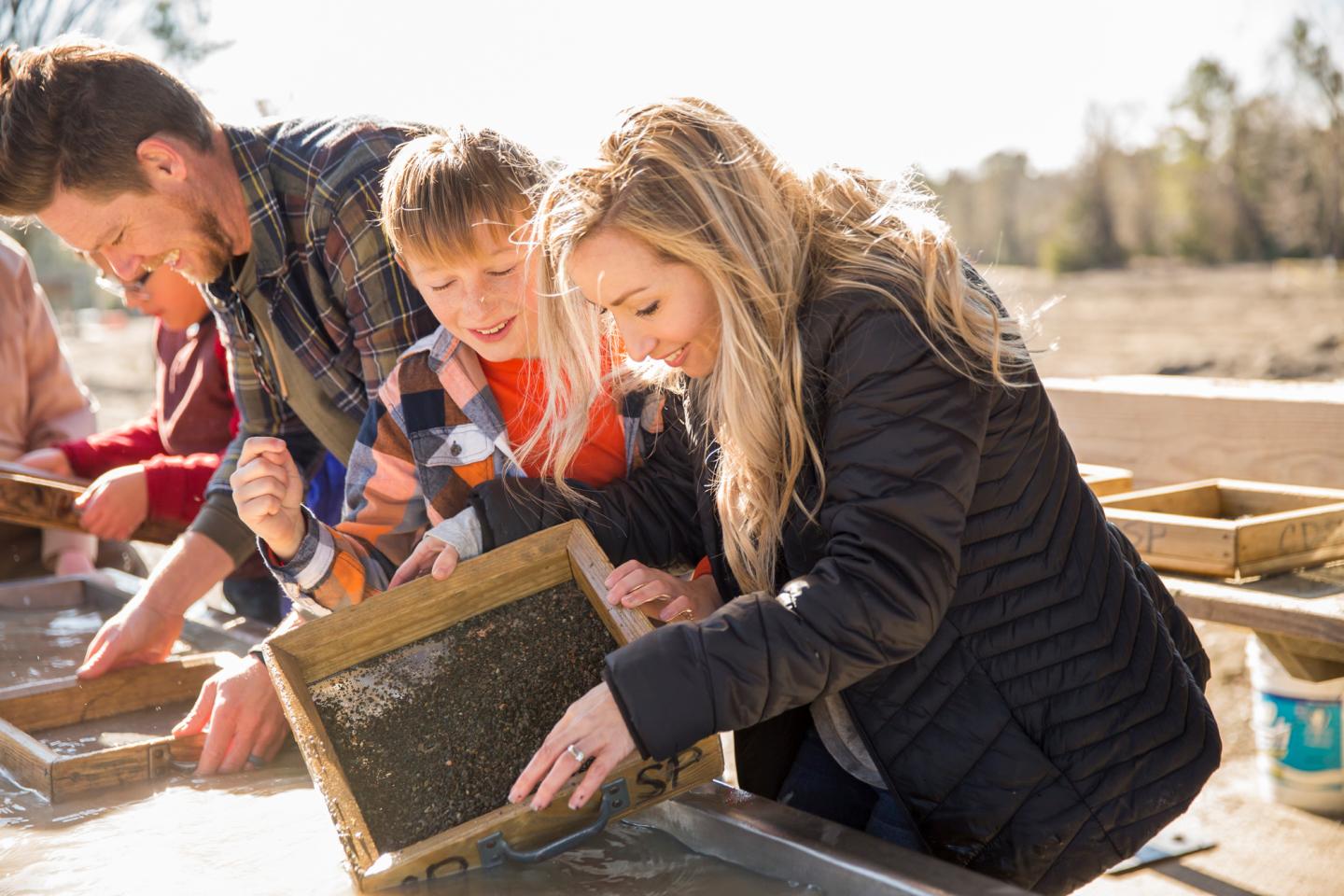 A family panning for gold in a sunny outdoor setting.