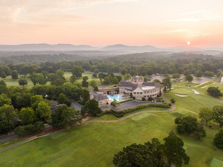 Golf course resort at sunrise with green lawns and distant hills.