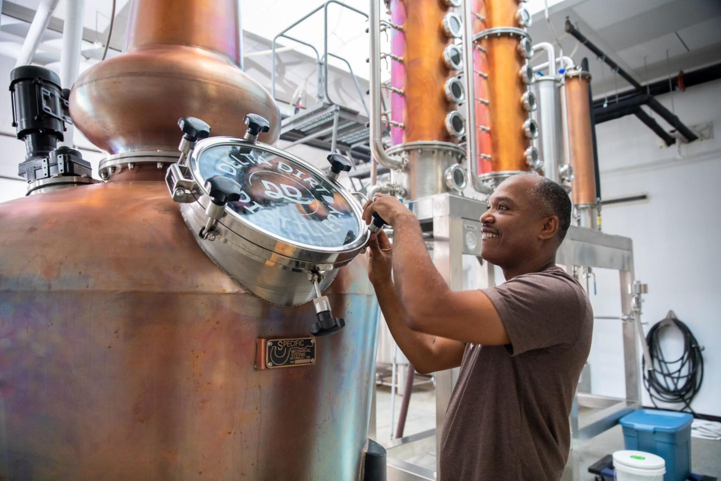 Man working on a large copper distillery tank.
