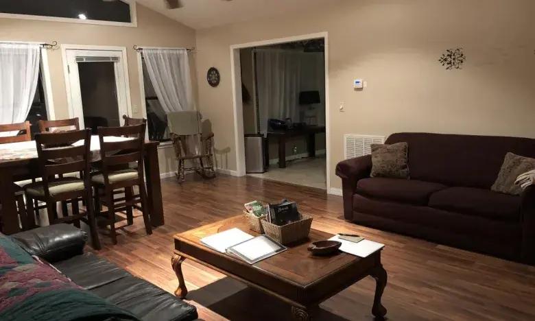 Cozy living room with a brown sofa, dining table, and wooden floor.