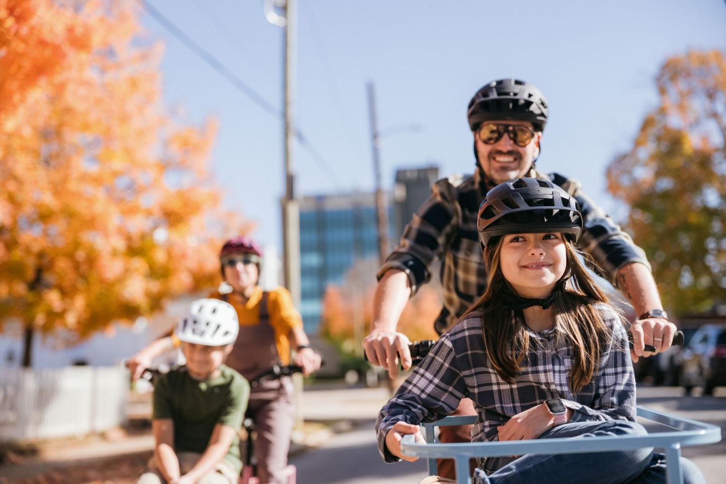 Family biking on a sunny autumn day with colorful leaves.