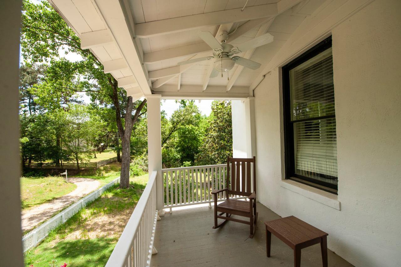 Covered porch with a rocking chair, small table, and ceiling fan.