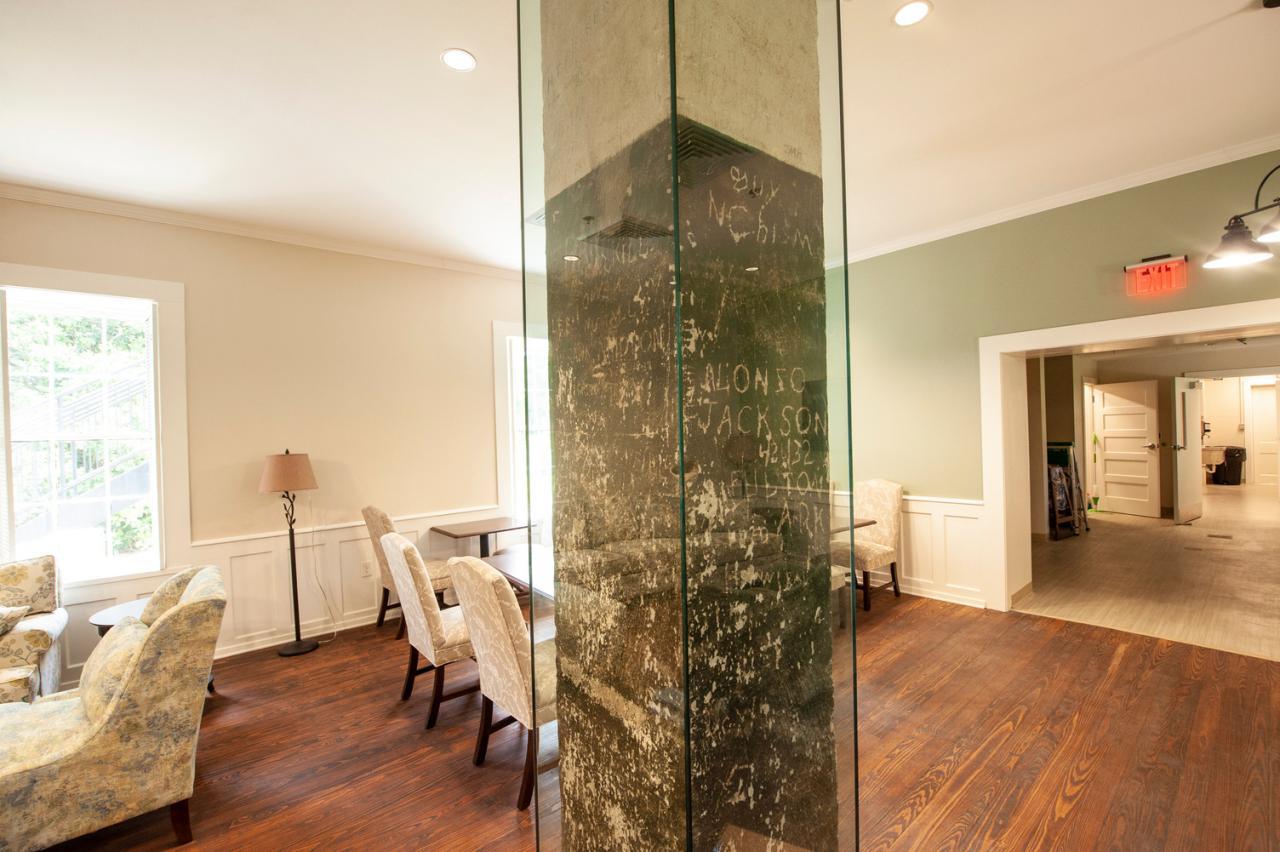 Bright room with chairs, a glass column, and wooden flooring.