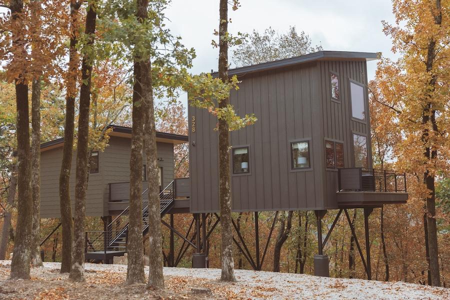 Modern treehouse in autumn forest, raised on stilts amidst colorful foliage.