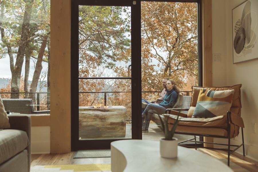 Cozy living room with a view of autumn trees through a large glass door.