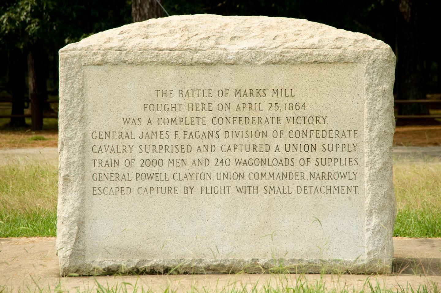 Stone monument with engraved historical text, set in a grassy area.