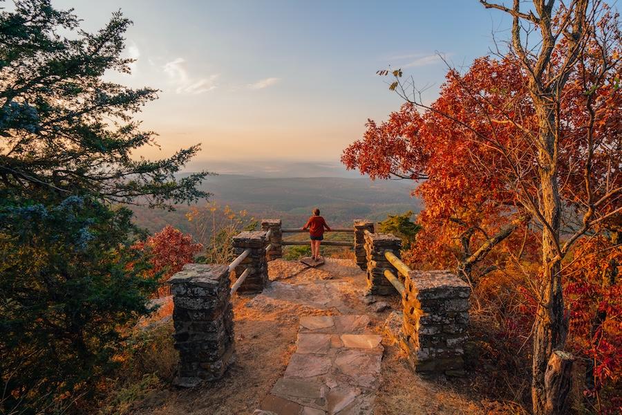 Pathway to scenic overlook with autumn trees and distant horizon at sunset.