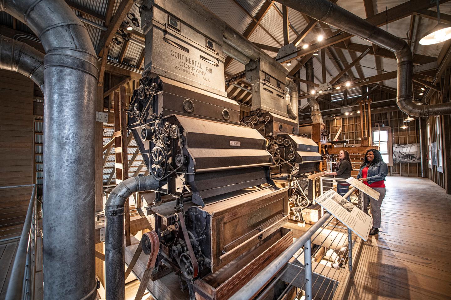 Historic industrial machinery in a museum setting with wooden beams.