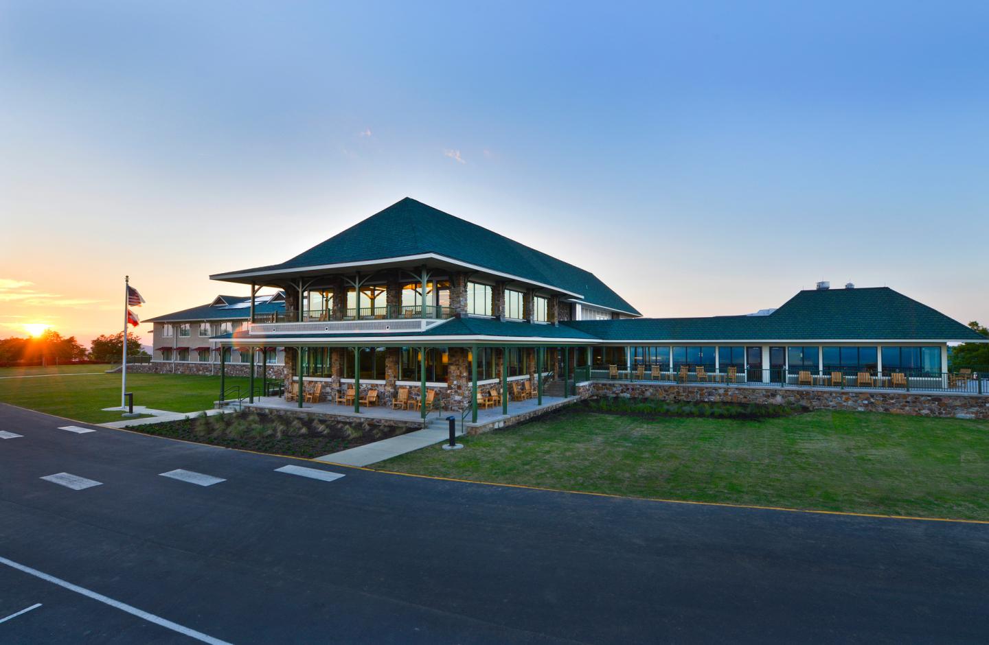 Large building with green roofs at sunset, surrounded by a grassy area.
