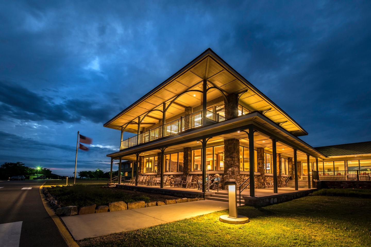 Modern building illuminated at dusk with a flag in the foreground.