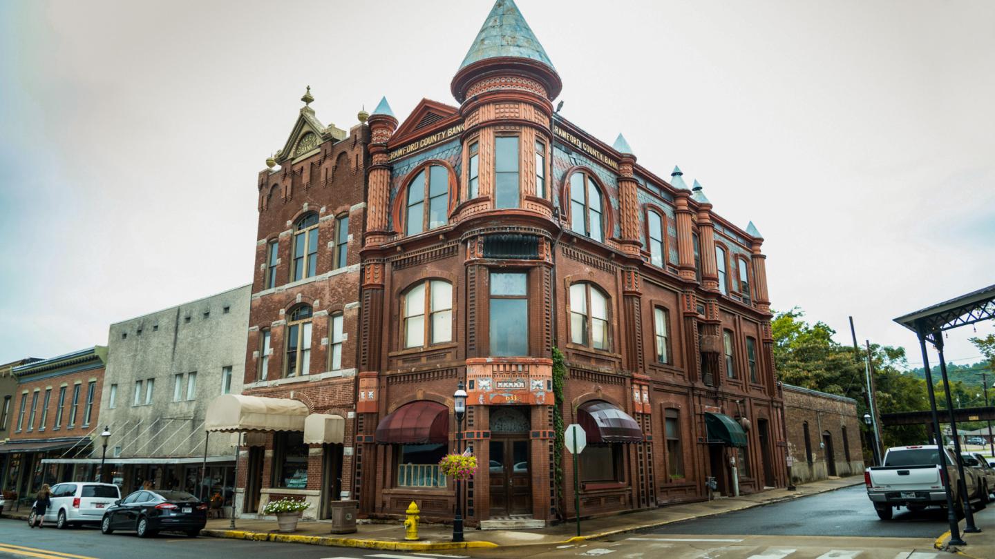 Historic red brick building with rounded turret on a street corner.