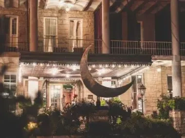 Historic building facade with crescent moon sculpture and warm lights.