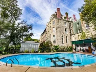 Historic stone building with outdoor pool under a blue sky.