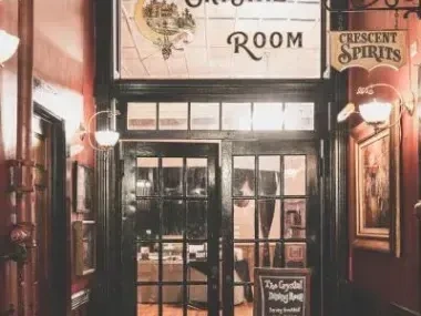 Entrance to a warmly lit bar with a vintage sign above.