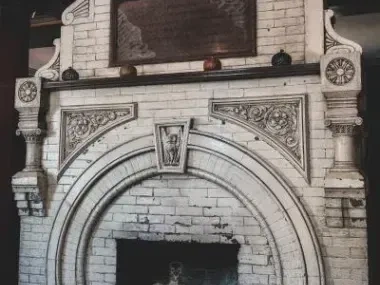 Ornate white brick fireplace with decorative carvings and a dark firebox.