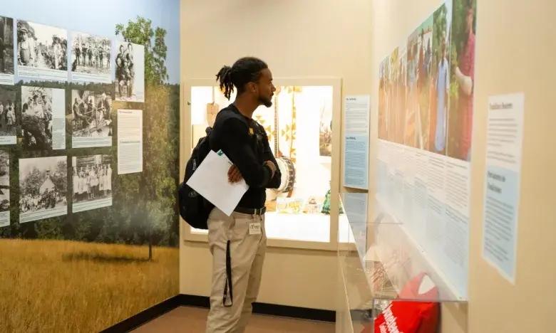 Man observes exhibits in a museum gallery.