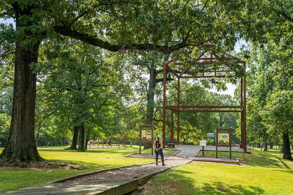 Rustic frame structure in a green park with trees and sunlight.