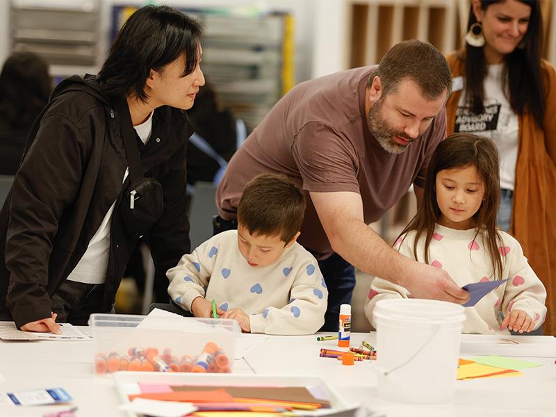 Adults and children engaged in a craft activity at a table.