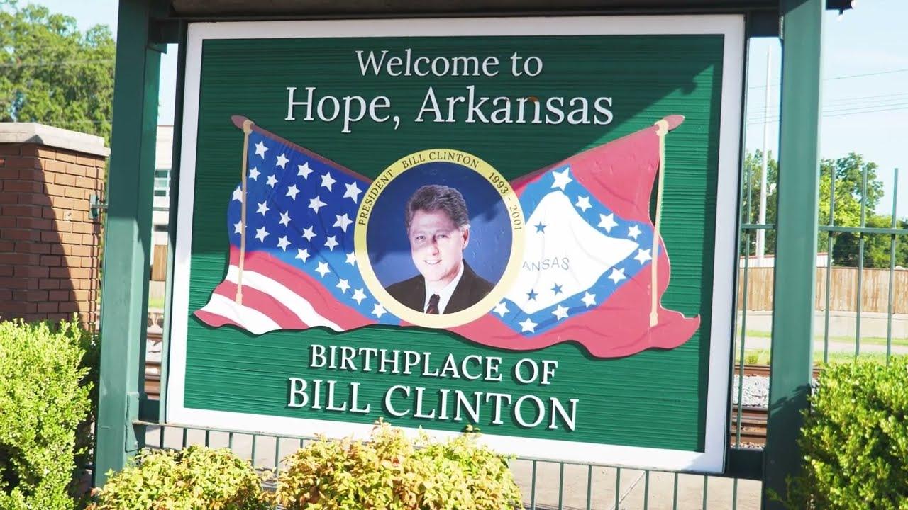 Sign reading "Welcome to Hope, Arkansas," with a portrait and flags.
